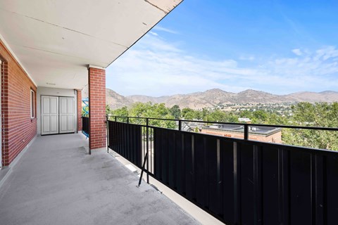 A balcony with a black railing and a view of the mountains.