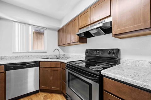 A kitchen with a black stove top oven and wooden cabinets.