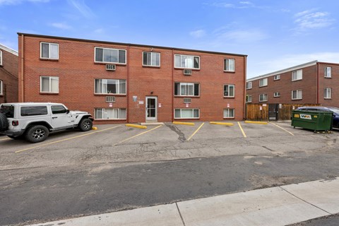 A parking lot in front of a red brick apartment building.
