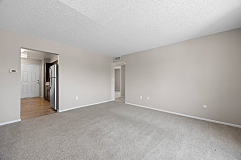A spacious room with a carpeted floor and white walls.