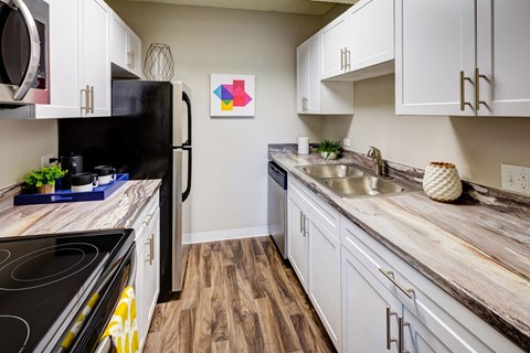 A kitchen with a black refrigerator and wooden floors.