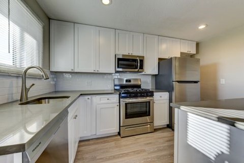 A kitchen with white cabinets and a stainless steel sink.