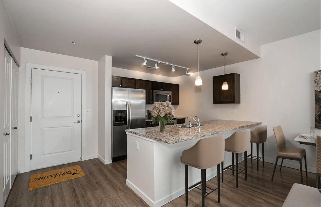 A kitchen with a white island and brown chairs.