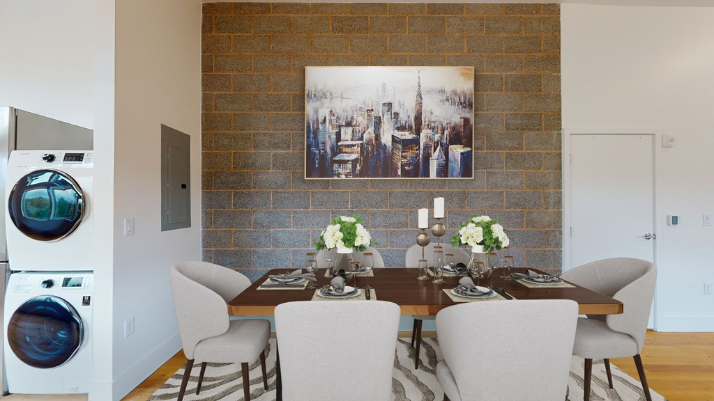 A dining room with a brick wall and a washing machine in the corner.