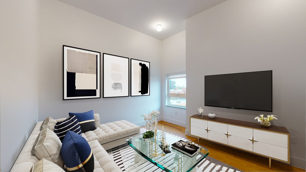 A living room with a white couch, a glass coffee table, and a black television.