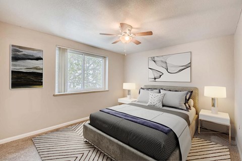 A bedroom with a large bed and a ceiling fan.