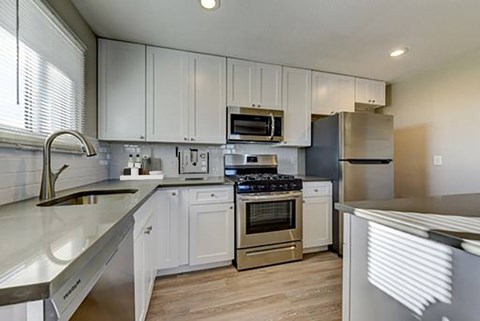 A modern kitchen with white cabinets and stainless steel appliances.