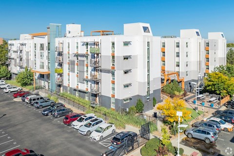 A parking lot with cars and apartment buildings in the background.