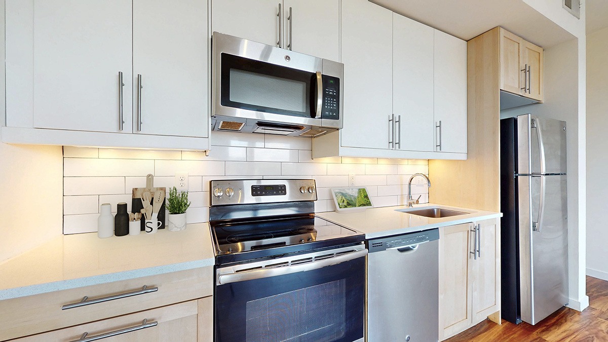 A modern kitchen with white cabinets and stainless steel appliances.