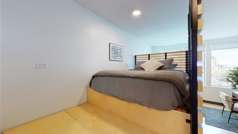 A bedroom with a bed, pillows, and a picture on the wall.