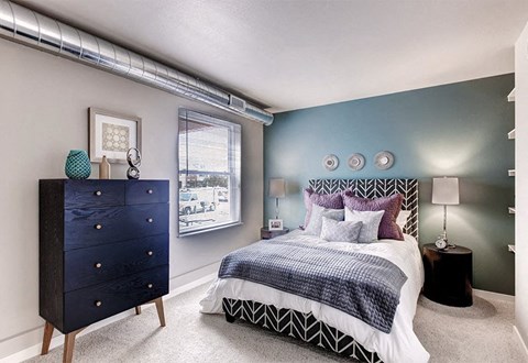 A bedroom with a bed, nightstand, and a dresser.