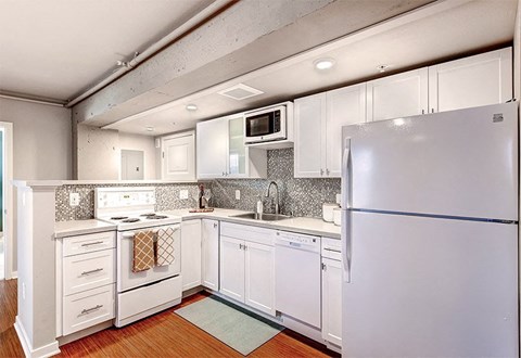 A white kitchen with a refrigerator on the right.