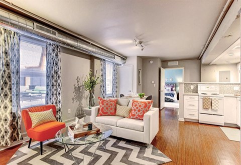 A living room with a white couch and a red chair.