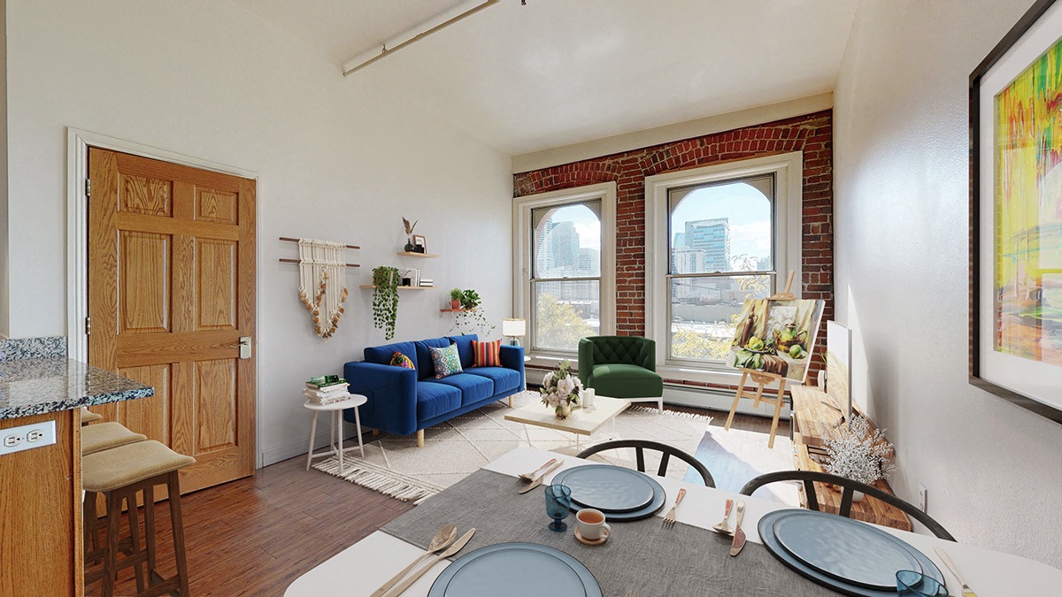 A living room with a blue couch and 2 large floor-to-ceiling windows showing downtown Denver views.