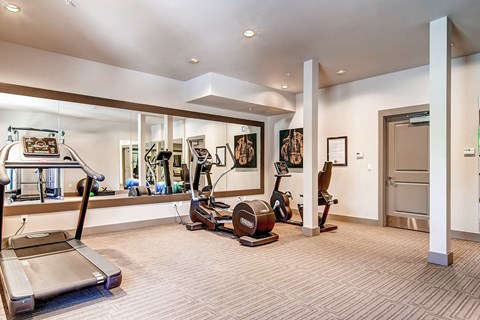 A spacious gym with treadmills, exercise bikes, and other equipment.