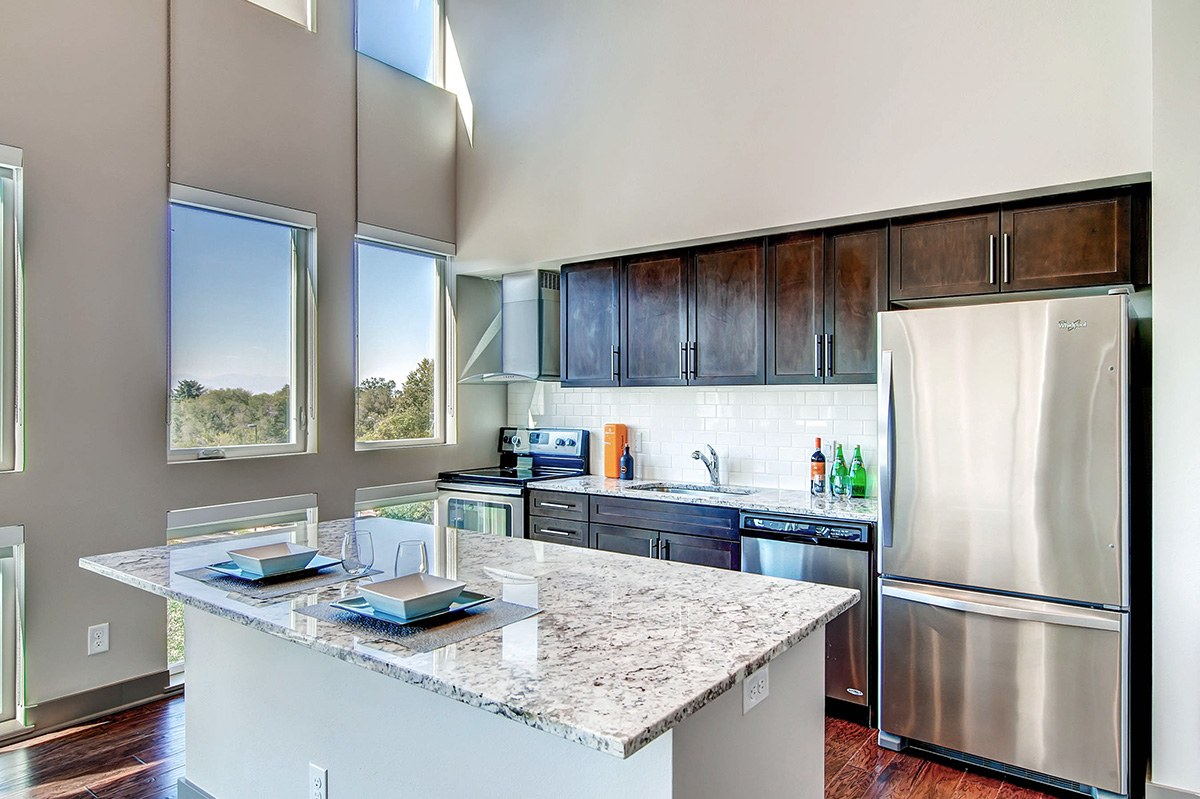 A kitchen with a marble countertop and stainless steel appliances.