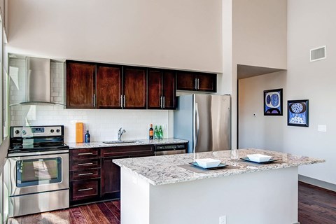 A kitchen with a stove top oven, refrigerator, and cabinets.