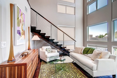 A living room with a white couch and a glass coffee table.