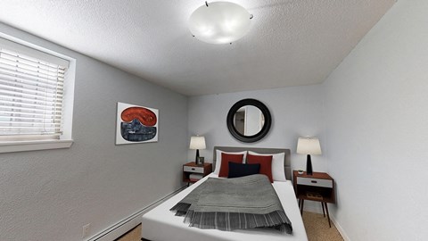 A bedroom with a bed, two nightstands, and a mirror.