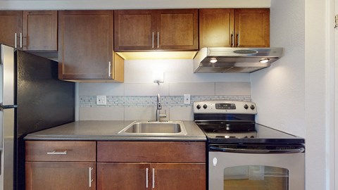 A kitchen with wooden cabinets and a stainless steel refrigerator.