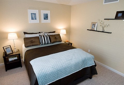 A bedroom with a large bed and two nightstands.
