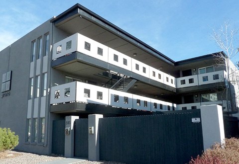 A modern building with a flat roof and a balcony on the second floor.