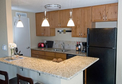 A kitchen with a granite counter top and wooden cabinets.