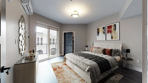 A bedroom with a large bed and a view of a city street through the window.