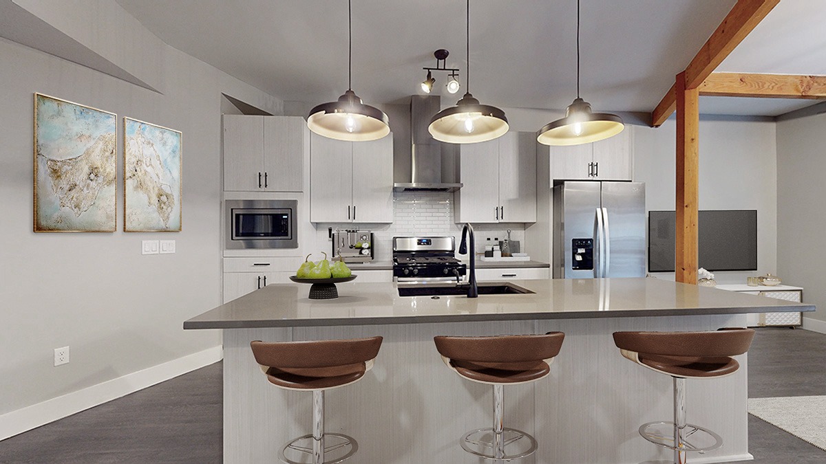 A modern kitchen with a bar stool and a painting on the wall.