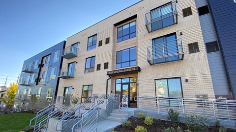 The image shows a modern building with a glass entrance and a sign that reads "Signalmen."