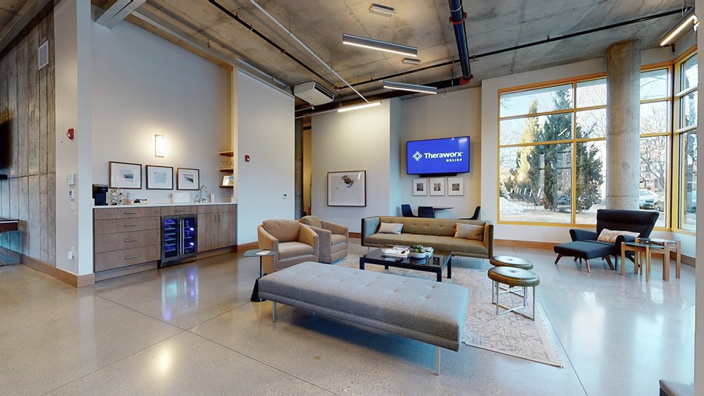 A spacious waiting room with a large couch and a flat screen TV mounted on the wall.