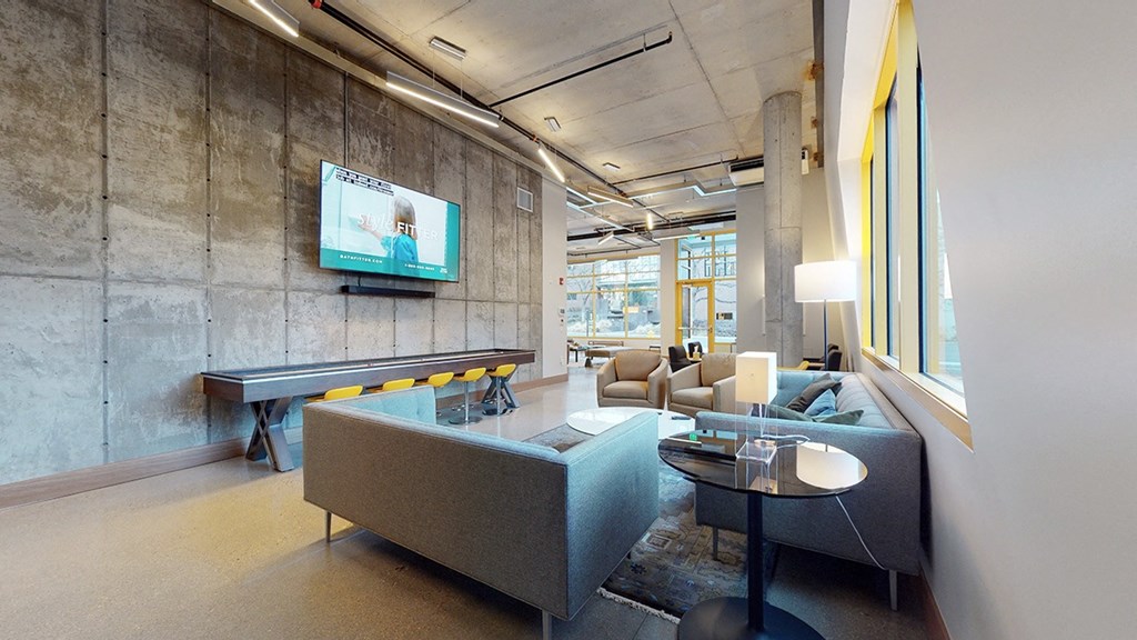 A modern living room with a grey couch and a television mounted on the wall.