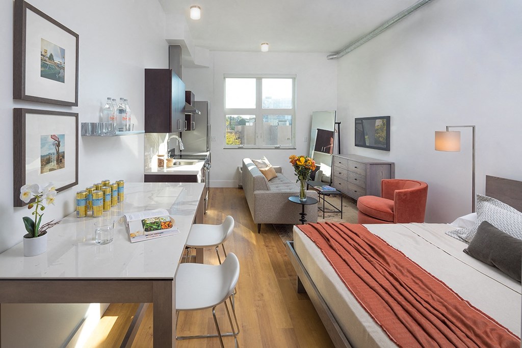 A modern bedroom with a large bed and a kitchen area.