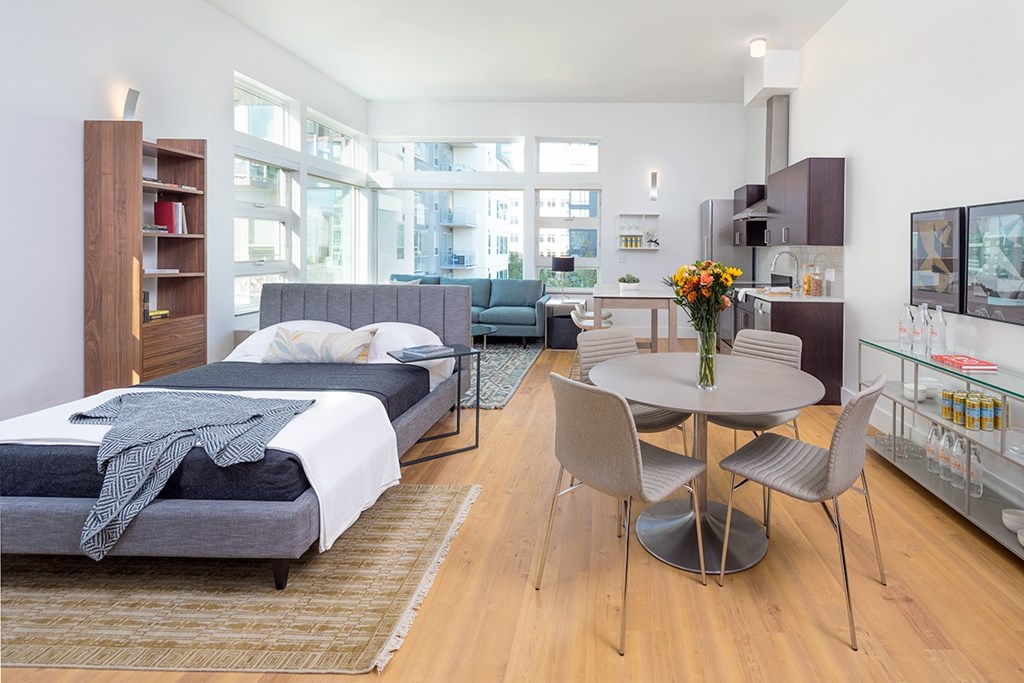 A bedroom with a bed, a chair, a table and a television.