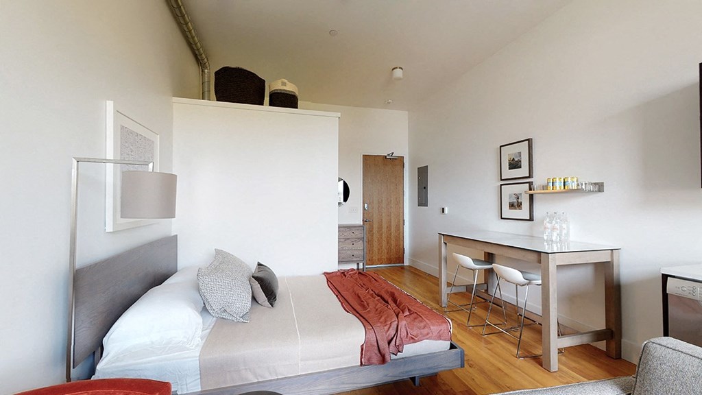 A bedroom with a bed, desk, and chair.