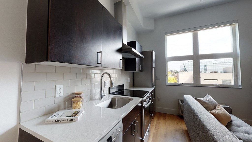 A kitchen with a grey couch and a white counter.