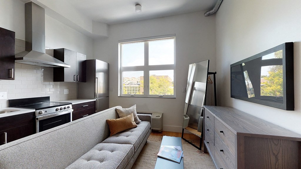 A modern kitchen with a grey couch and a window.
