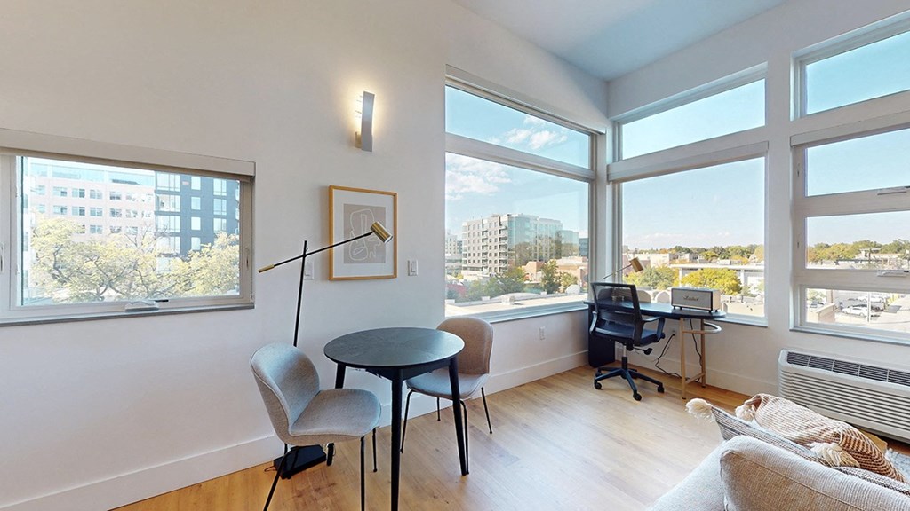 A room with a table, chairs, and a laptop on a desk.