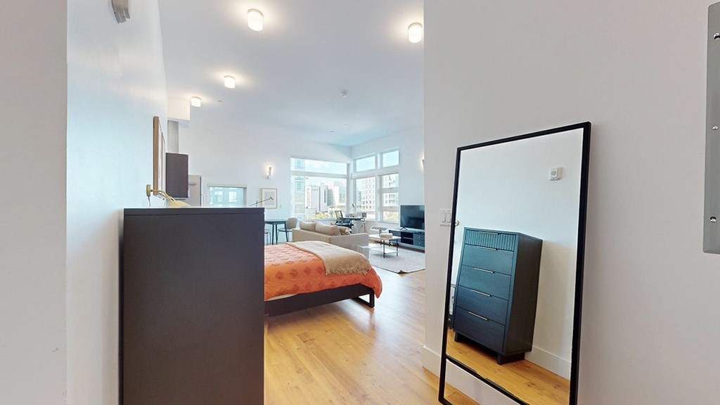 A bedroom with a bed, dresser and mirror.