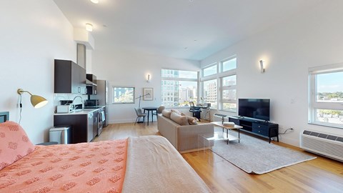 A modern living room with a red patterned sofa and a kitchen area with a microwave and oven.