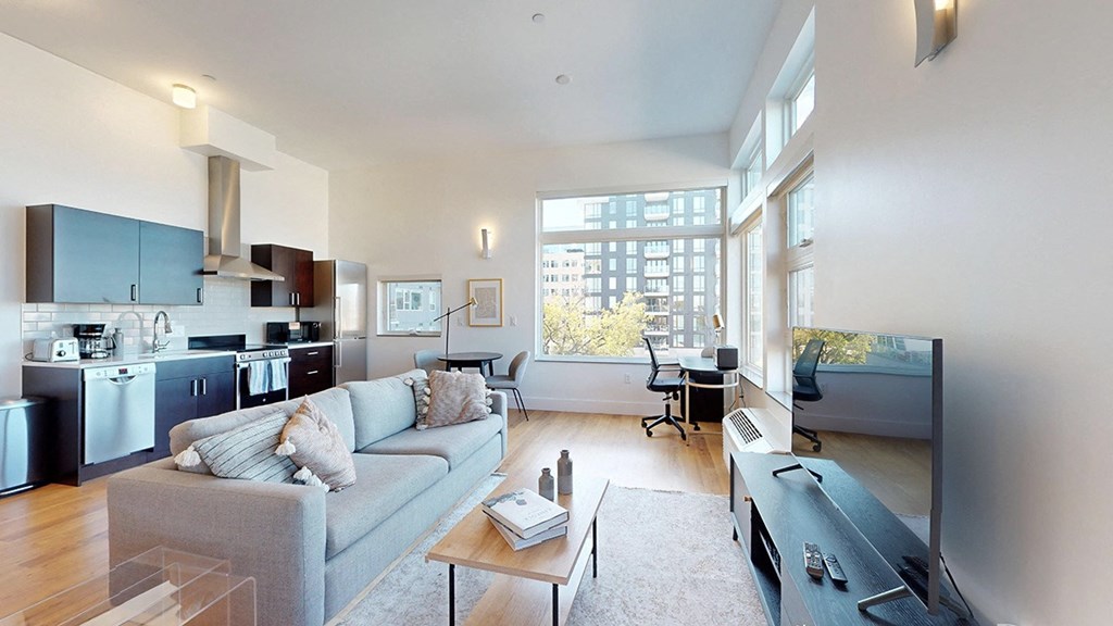 A modern living room with a grey couch and a large window.