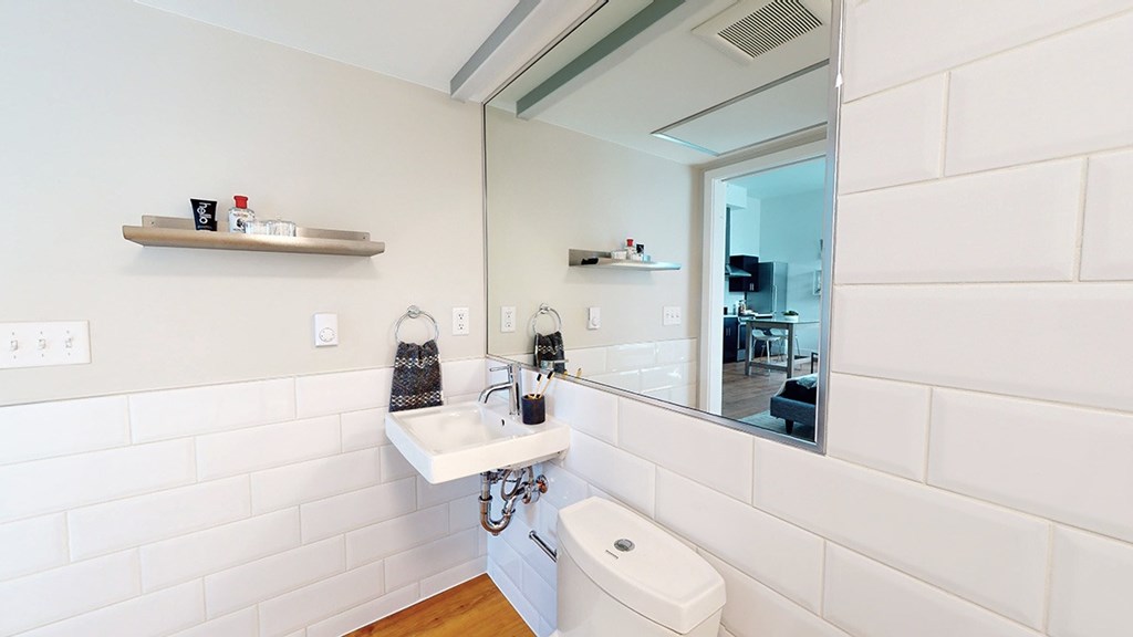 A white bathroom with a sink, mirror, and toilet.