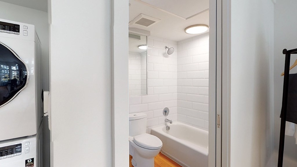 A white bathroom with a washer and dryer in the corner.