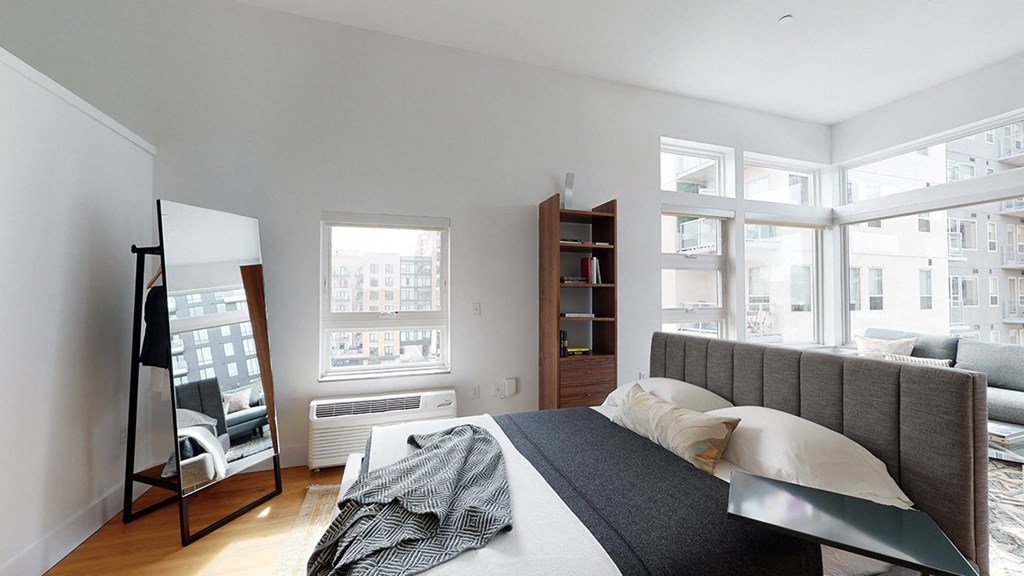 A bedroom with a large bed and a window overlooking a cityscape.