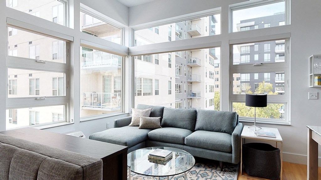 A grey couch with a glass table in front of it.