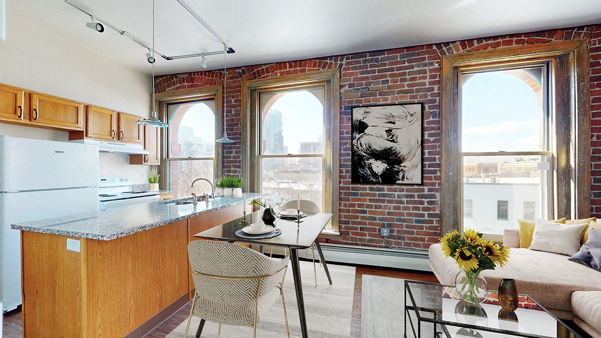 Open-plan kitchen with island,  dining table and living area with sofa. 3 large floor-to-ceiling windows look out on to the city landscape.