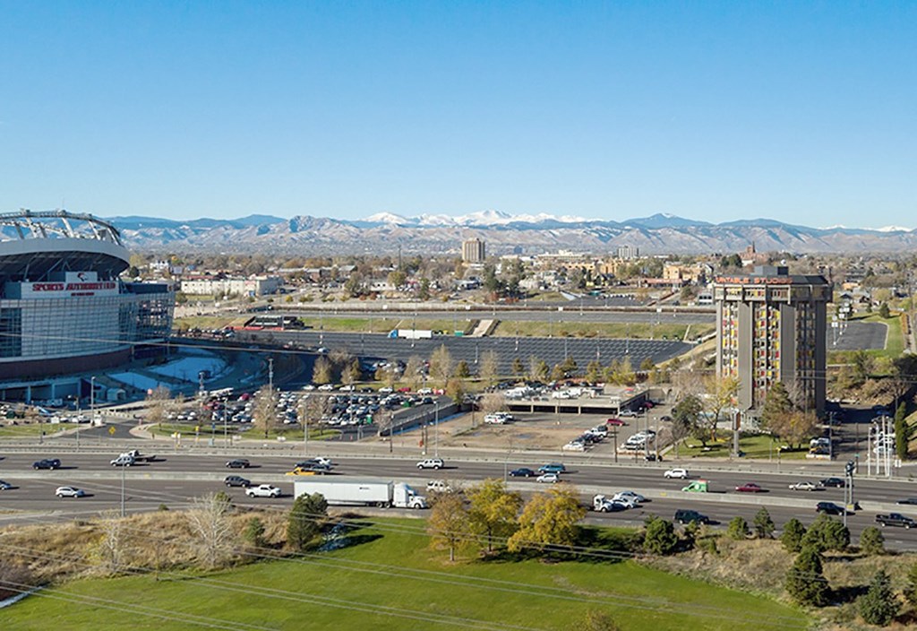 A cityscape with a large stadium and mountains in the background.