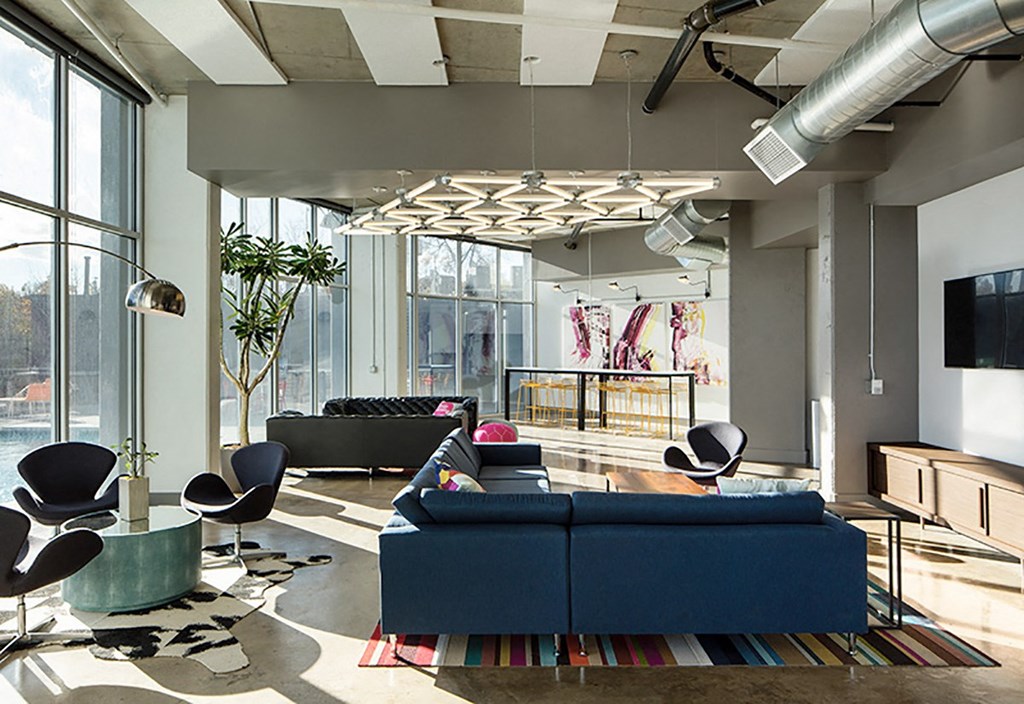 A modern living room with a blue couch and a TV on the wall.