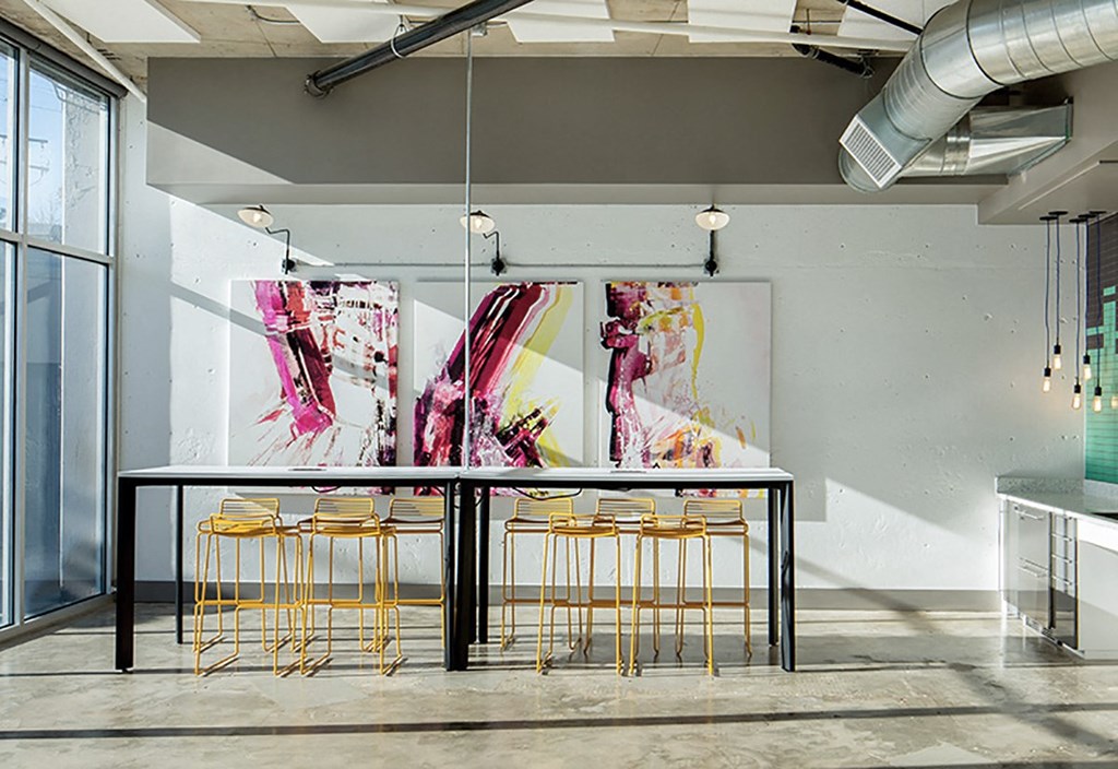 A room with a table and chairs and a painting on the wall.