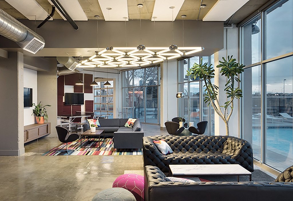 A modern living room with a black sofa and a glass wall.
